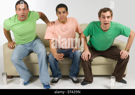 Three men watching television Stock Photo