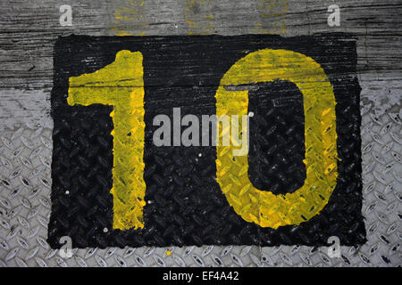Top view of the number 10 painted in a stencil style in yellow color on the ground. It's in a black square Stock Photo