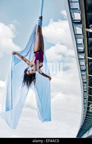 Young woman gymnast. On city and sky background. Stock Photo