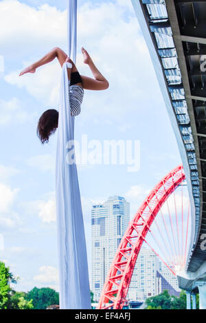 Young woman gymnast. On city and sky background. Stock Photo