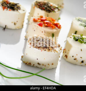 a plate with some different cheese canapes topped with different spices Stock Photo