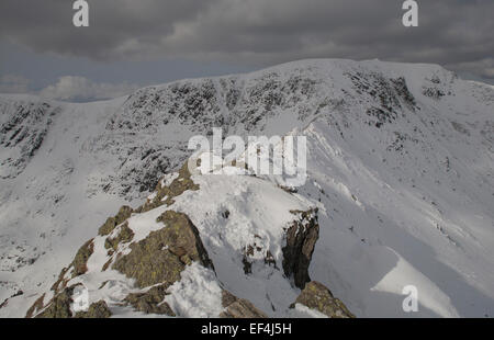 The snowy ridge of Striding Edge leads up to the summit of Helvellyn, a notorious place for accidents and rescues in the English Stock Photo