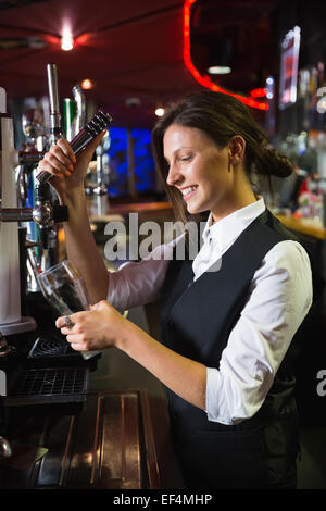 Happy barmaid pulling a pint of beer Stock Photo