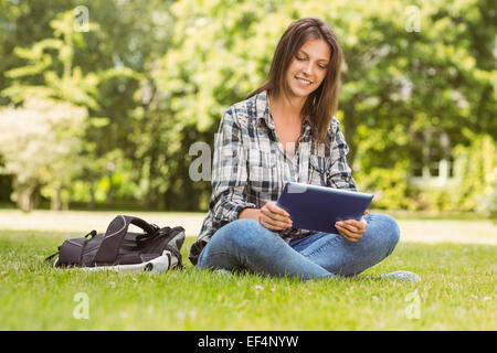 Smiling student sitting and using tablet pc Stock Photo