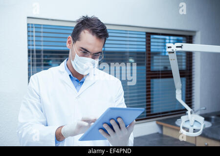 Dentist in surgical mask using digital tablet Stock Photo