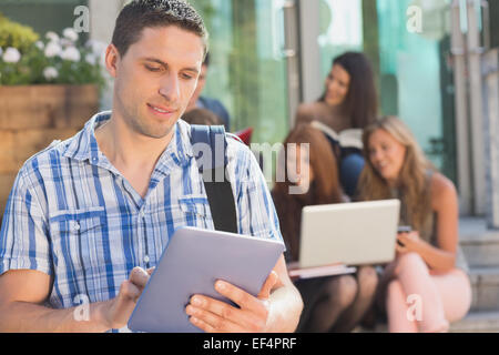 Happy student using his tablet pc on campus Stock Photo