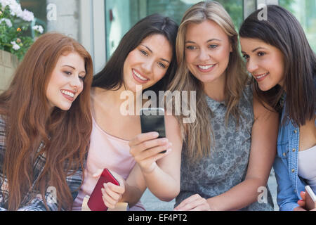 Happy students sitting in a row texting Stock Photo