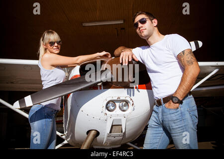 Young couple standing by propeller airplane Stock Photo