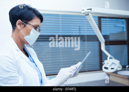 Dentist in surgical mask using digital tablet Stock Photo
