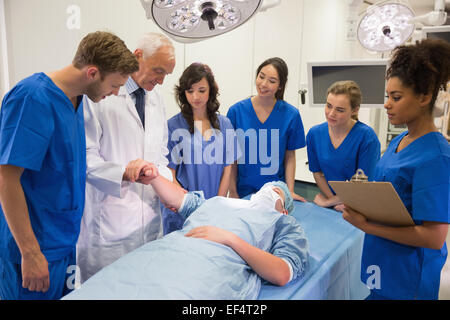 Medical students and professor checking pulse of student Stock Photo
