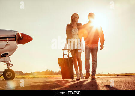 Young couple with luggage, propeller airplane in foreground Stock Photo