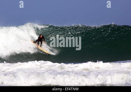 Surfer riding large waves off Porthmeor beach, St Ives, Cornwall Stock Photo