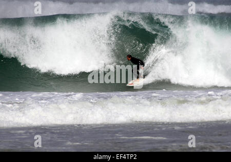 Surfer riding large waves off Porthmeor beach, St Ives, Cornwall Stock Photo