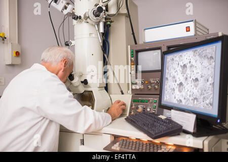 Biochemist using large microscope and computer Stock Photo