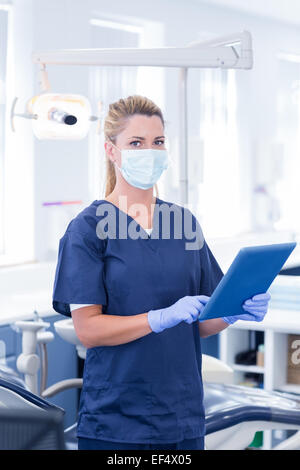 Dentist in mask using her tablet and looking at camera Stock Photo