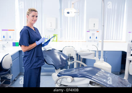 Smiling dentist working on tablet pc and looking at camera Stock Photo