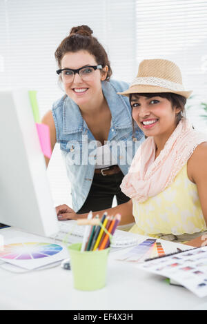 Smiling colleagues brainstorming and using computer Stock Photo