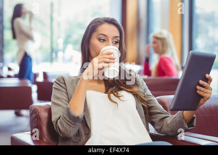 Student using digital tablet and holding disposable cup Stock Photo