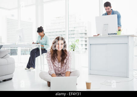 Happy businesswoman sitting on the floor using laptop Stock Photo