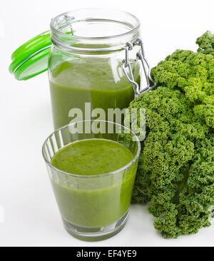 Green smoothie in a glass and in a open jar with fresh kale. A raw, healthy and vegan beverage made of green leafs and fruits. Stock Photo