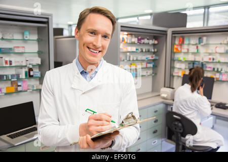 Happy pharmacist writing on clipboard Stock Photo