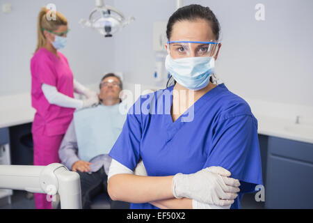 Dentist wearing surgical mask and safety glasses arms crossed Stock Photo