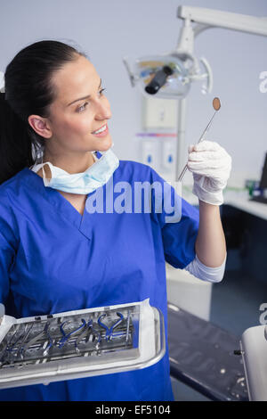 Smiling dentist holding tray and looking angle mirror Stock Photo