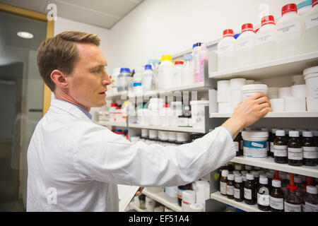 Handsome pharmacist taking medicine from shelf Stock Photo