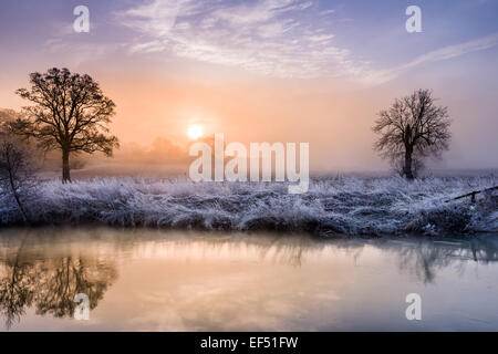 The sun rises above the mist to light up the fields on the river Avon near Malmesbury in Wiltshire. Stock Photo