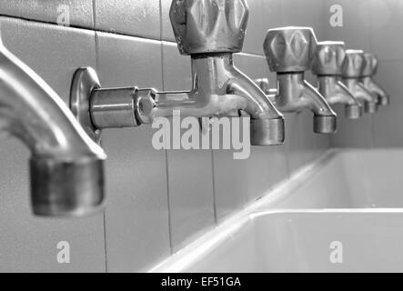 many steel taps in white ceramic sink Stock Photo