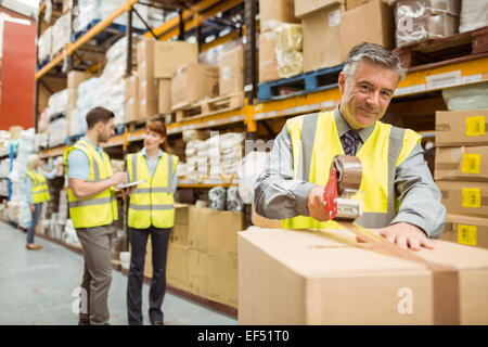 Warehouse worker sealing cardboard boxes for shipping Stock Photo