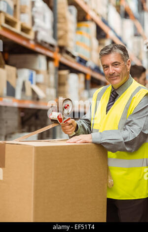 Warehouse worker sealing cardboard boxes for shipping Stock Photo