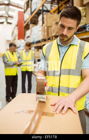 Warehouse worker sealing cardboard boxes for shipping Stock Photo