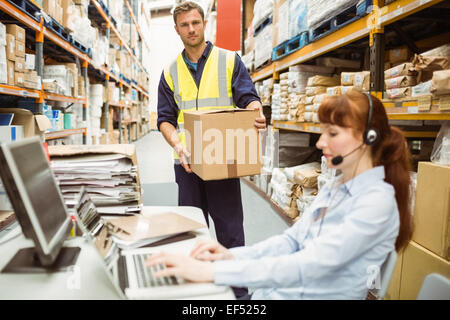 Warehouse manager wearing headset using laptop Stock Photo