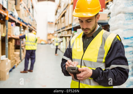 Focused worker wearing yellow vest using handheld Stock Photo
