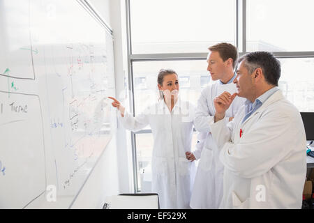 Science students and lecturer looking at whiteboard Stock Photo