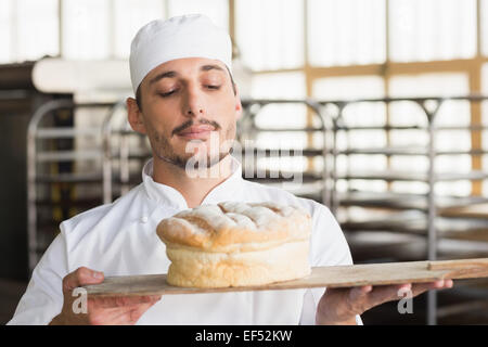 Baker smelling a freshly baked loaf Stock Photo