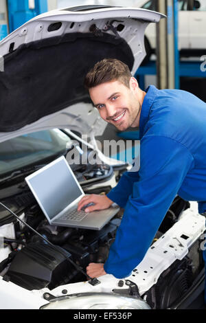 Mechanic using laptop on car Stock Photo
