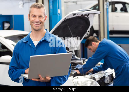 Smiling mechanic using a laptop Stock Photo