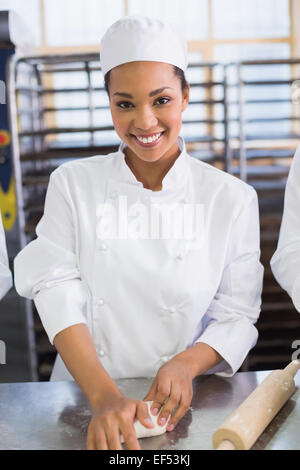 Happy baker kneading dough on counter Stock Photo