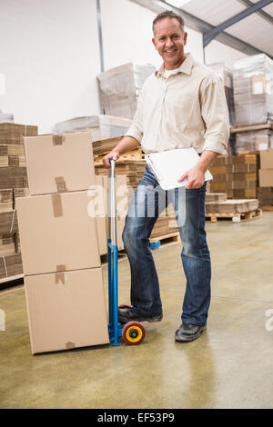 Delivery man leaning on trolley of boxes Stock Photo
