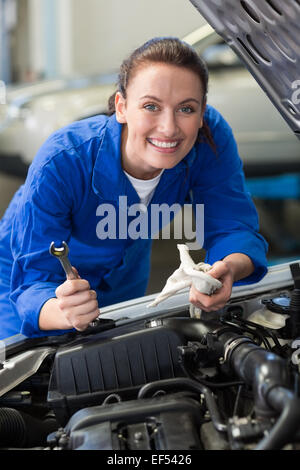 Mechanic smiling at the camera fixing engine Stock Photo