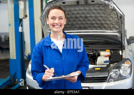 Smiling mechanic writing on clipboard Stock Photo