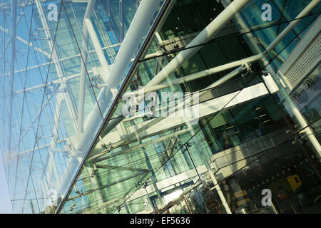 Reflections in a modern glass building. This architecture example is of a building on Tower Bridge Approach, London. The frontage is made of steel and tension cables in an ordered grid. Stock Photo