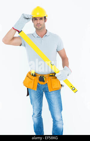 Carpenter holding spirit level while wearing hard hat Stock Photo