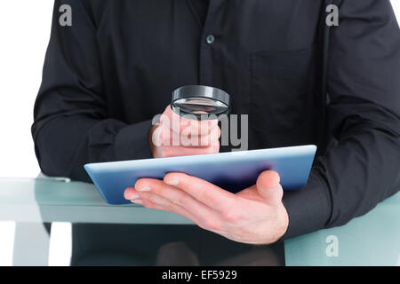 Businessman looking at tablet with magnifying glass Stock Photo