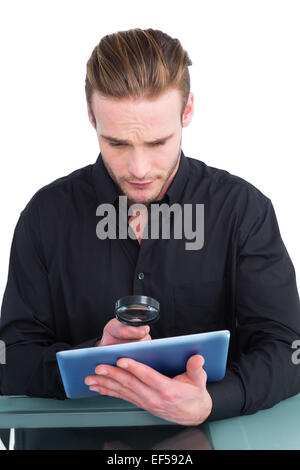 Businessman looking at tablet with magnifying glass Stock Photo