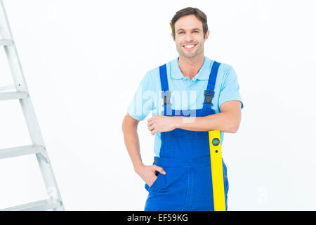 Confident carpenter leaning on spirit level Stock Photo