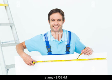 Happy carpenter measuring blank bill board Stock Photo