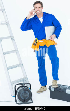 Electrician with leg on tool box using mobile phone Stock Photo